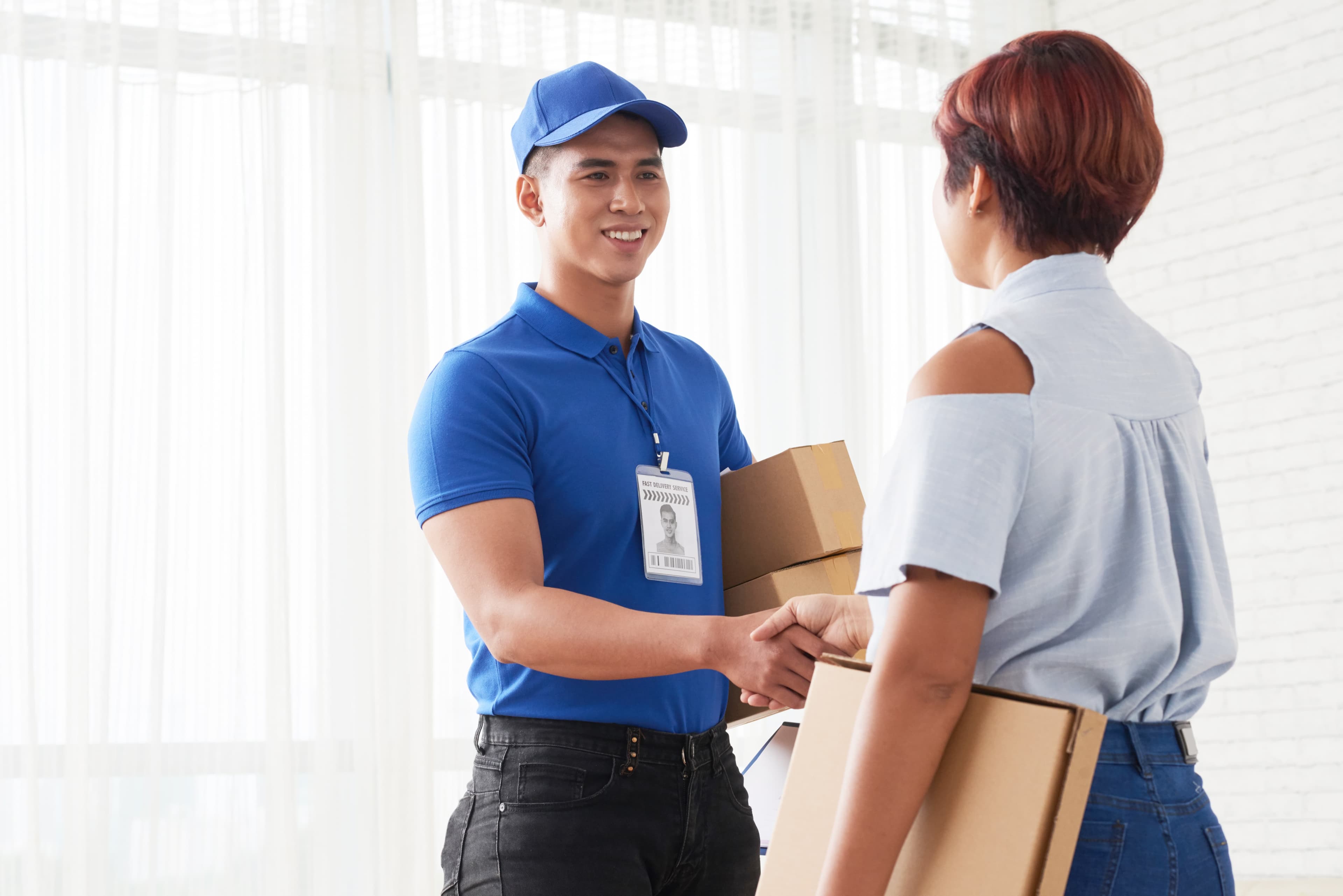 Happy delivery guy handing package to a woman.